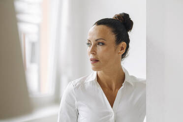 Close-up of thoughtful businesswoman standing by wall in home office - JOSEF01285