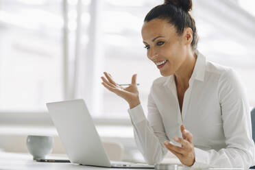 Smiling female entrepreneur using laptop on desk in home office - JOSEF01300