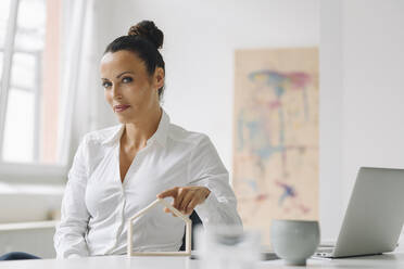 Selbstbewusste Geschäftsfrau mit Hausmodell auf dem Schreibtisch im Home Office - JOSEF01320