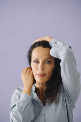 Close-up of confident mid adult woman posing against purple background - JOSEF01385