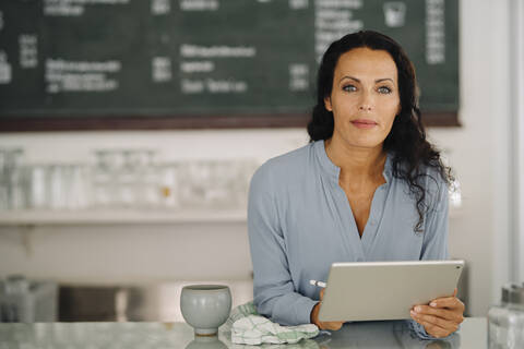 Confident female barista using digital tablet on counter while standing in restaurant stock photo
