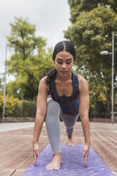 Junge flexible Frau übt Yoga auf einer Matte im Park - DSIF00010