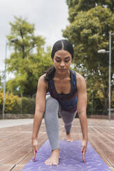 Young flexible woman practicing yoga on mat at park - DSIF00010