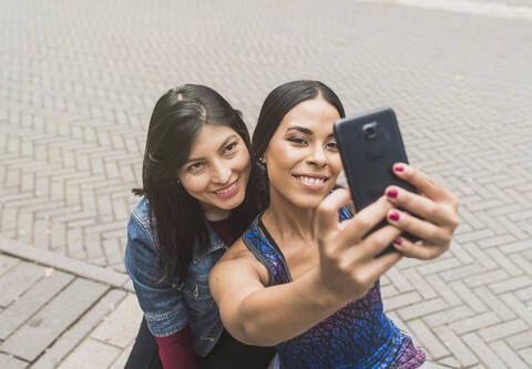Smiling young woman taking selfie with friend stock photo