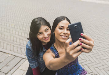 Lächelnde junge Frau nimmt Selfie mit Freund - DSIF00018