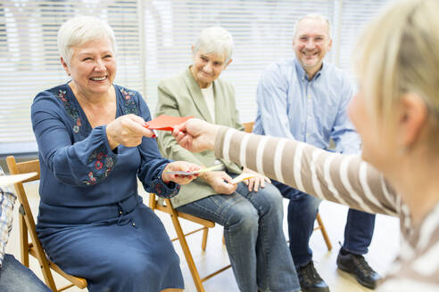 Senioren im Altersheim nehmen an einer Gruppentherapie mit bunten Papierkarten teil - WESTF24568