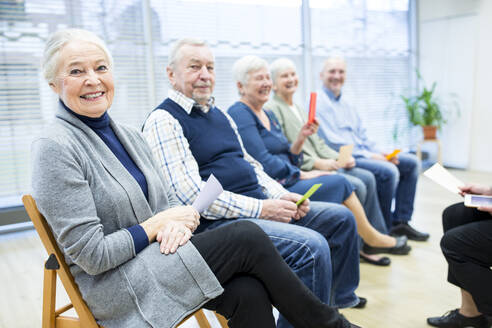 Senioren im Altersheim nehmen an einer Gruppentherapie mit bunten Papierkarten teil - WESTF24578