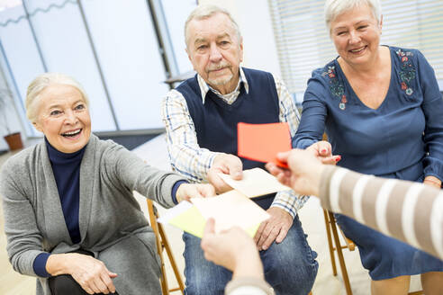 Senioren im Altersheim nehmen an einer Gruppentherapie mit bunten Papierkarten teil - WESTF24582