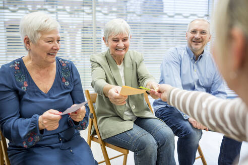 Senioren im Altersheim nehmen an einer Gruppentherapie mit bunten Papierkarten teil - WESTF24584