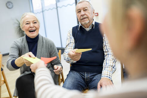 Senioren im Altersheim nehmen an einer Gruppentherapie mit bunten Papierkarten teil - WESTF24585