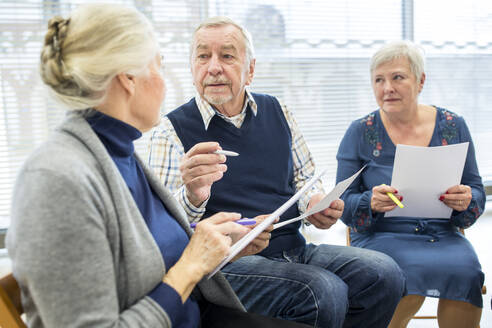 Senioren in einer Therapiegruppe in einem Seniorenheim, die Notizen auf Zetteln notieren - WESTF24602