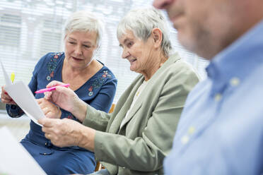Senioren in einer Therapiegruppe in einem Seniorenheim, die Notizen auf Zetteln notieren - WESTF24605