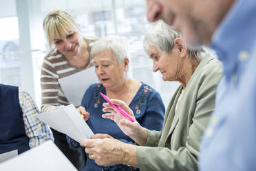 Senioren in einer Therapiegruppe in einem Seniorenheim, die Notizen auf Zetteln notieren - WESTF24606