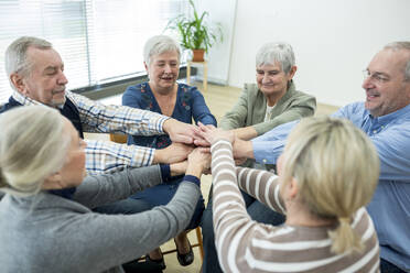 Gruppe aktiver Senioren, die sich die Hände reichen, als Symbol der Solidarität - WESTF24612