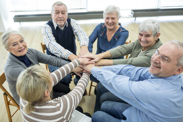 Gruppe aktiver Senioren, die sich die Hände reichen, als Symbol der Solidarität - WESTF24614