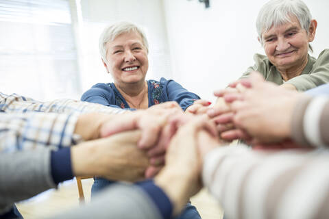 Group of active seniors stacking hands, symbolizing solidarity stock photo