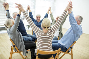 Gruppe von Senioren bei der Stuhlgymnastik mit einem Lehrer in einem Seniorenheim - WESTF24630