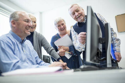 Aktive Senioren, die einen Computerkurs besuchen, den Kursleiter beobachten und sich Notizen machen, lizenzfreies Stockfoto