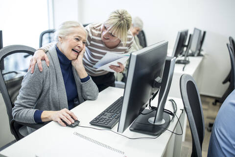 Aktive Senioren, die einen Computerkurs besuchen, ein Lehrer gibt Ratschläge, lizenzfreies Stockfoto