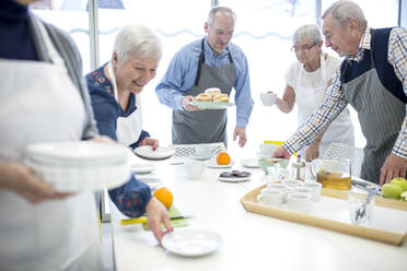 Eine Gruppe von Senioren deckt den Tisch für das Kaffeekränzchen im Altersheim - WESTF24687