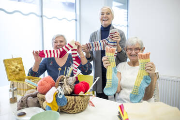 Senior women knitting toghether in needlework group of retirement home - WESTF24693