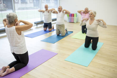 Gruppe aktiver Senioren, die gemeinsam Yoga praktizieren - WESTF24702