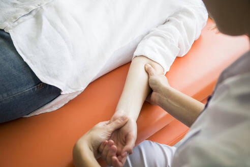 Hands of female physiotherapist massaging the arm of a woman - ABZF03242