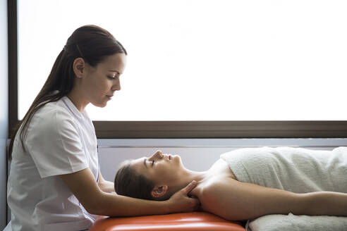 Hands of female physiotherapist massaging the neck of a woman - ABZF03249