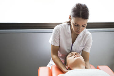 Hands of female physiotherapist massaging the neck of a woman - ABZF03252