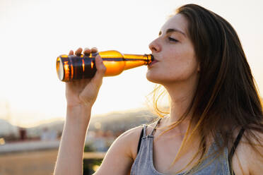 Happy woman holding brown glass bottle - ADSF00425