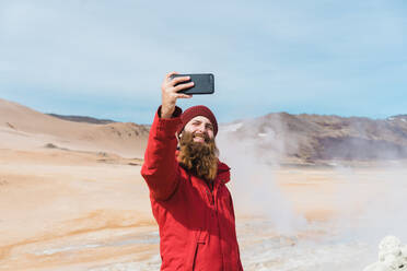 Mann steht mit Smartphone am Geysir - ADSF00481