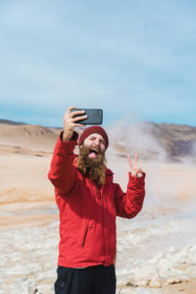 Man standing with smartphone at geyser - ADSF00482