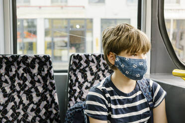 Boy wearing protective mask in tram - MMFF01287