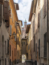 Italy, Province of Cremona, Cremona, Old empty alley with towers of Cremona Cathedral in background - MCVF00499