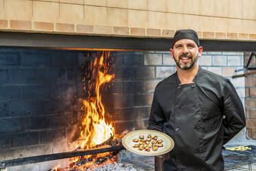 Traditionelle Küche im Restaurant ktichen, Chefkoch zeigt Teller mit gegrillten Meeresfrüchten - DLTSF00847