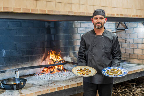 Traditionelle Küche im Restaurant ktichen, Chefkoch zeigt Teller mit gegrillten Meeresfrüchten - DLTSF00848