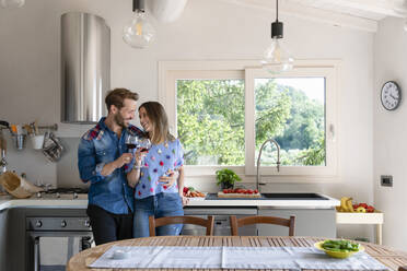 Happy mid adult couple enjoying wine while standing in kitchen at home - EIF00029