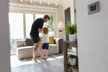 Glücklicher Mann spielt mit seinem Sohn auf dem Sofa im Wohnzimmer zu Hause - EIF00032