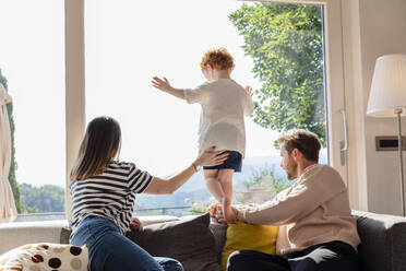 Parents and son looking out through window at home - EIF00048