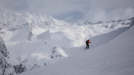 Seitenansicht eines nicht erkennbaren Wanderers mit Stöcken, der auf einem verschneiten Hügel läuft. - ADSF00533