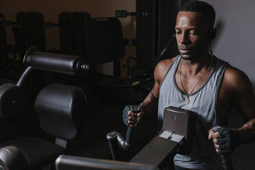 Black man exercising on machine in gym - ADSF00551