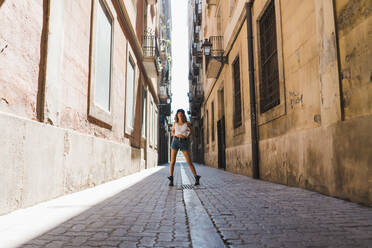 Charming curly woman in shorts and brutal boots standing playfully on paved street having fun - ADSF00615