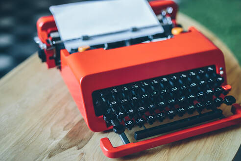 Close-up bright red typewriter on small table with paper sheet inserted - ADSF00627
