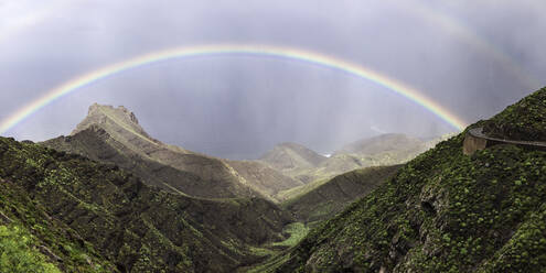 Lebendiger Regenbogen am bewölkten Himmel über einem majestätischen Gebirgskamm auf der Insel Gran Canaria, Spanien - ADSF00638