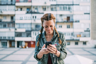 Pretty red-haired girl with braids using mobile phone. It is in the city of Madrid Spain. - ADSF00710