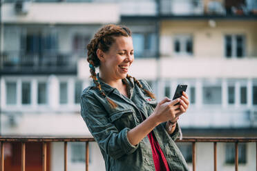 Pretty red-haired girl with braids using mobile phone. It is in the city of Madrid Spain. - ADSF00711