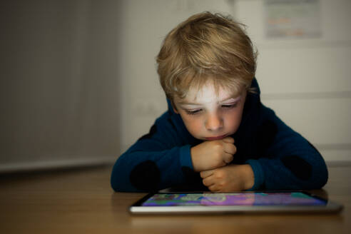 Kaukasischer Junge schaut Cartoons auf einem Tablet - ADSF00741