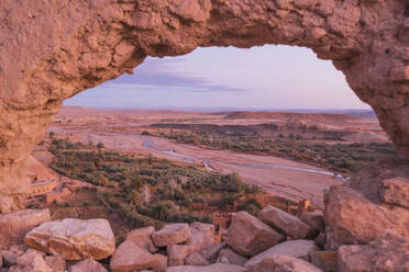 Felsen eines hohen Berges mit kreisrundem Loch und malerischem Blick auf ein Tal mit schmalem Fluss und Wüste in Marrakesch, Marokko - ADSF00746