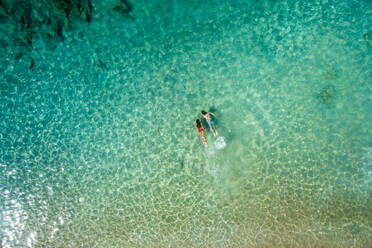 Luftaufnahme eines entspannten Mannes und einer entspannten Frau, die zusammen unter Wasser in schönem, klarem, türkisfarbenem Meerwasser an einem sonnigen Sommertag in La Graciosa, Kanarische Inseln, schwimmen - ADSF00773