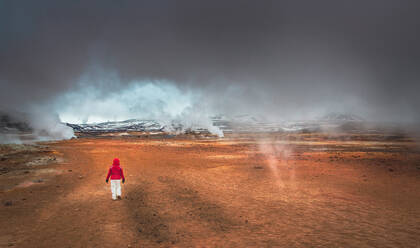 Back view of anonymous person walking in amazing valleys near majestic geysers in Iceland - ADSF00882